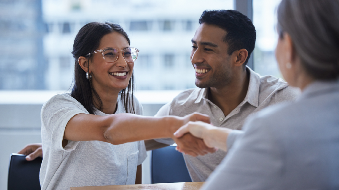 decorative image of a couple shaking hands with someone behind a desk