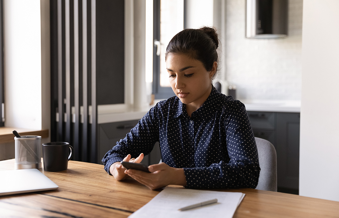 young woman at a desk holding a mobile phone