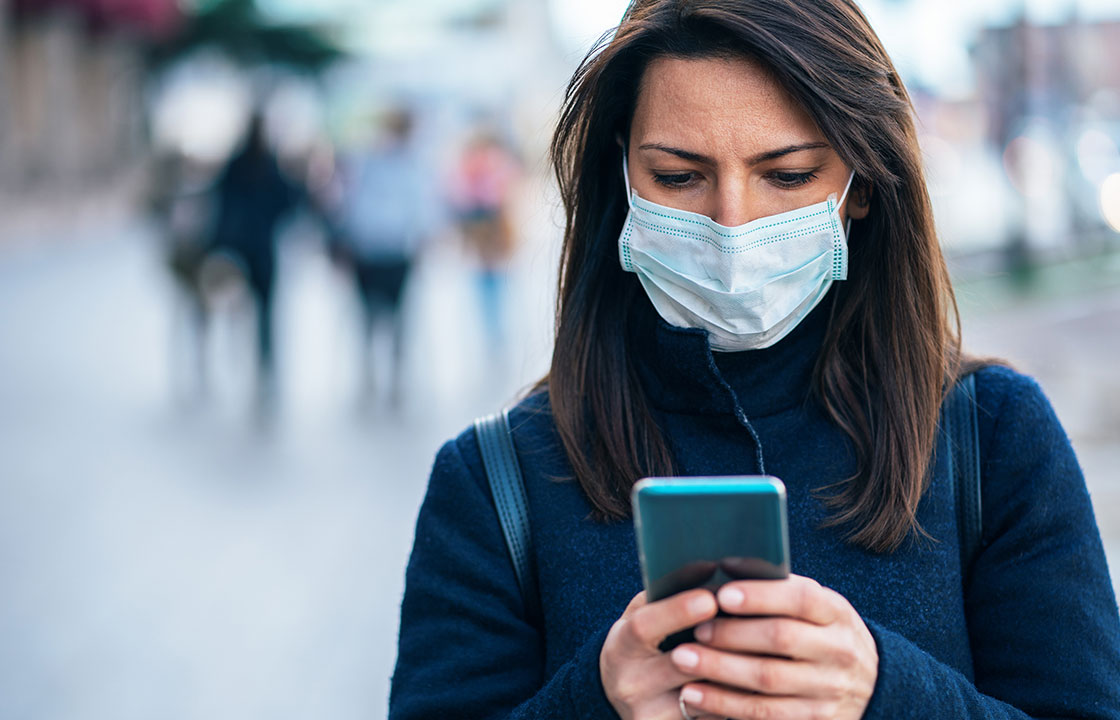 woman wearing mask holding mobile phone